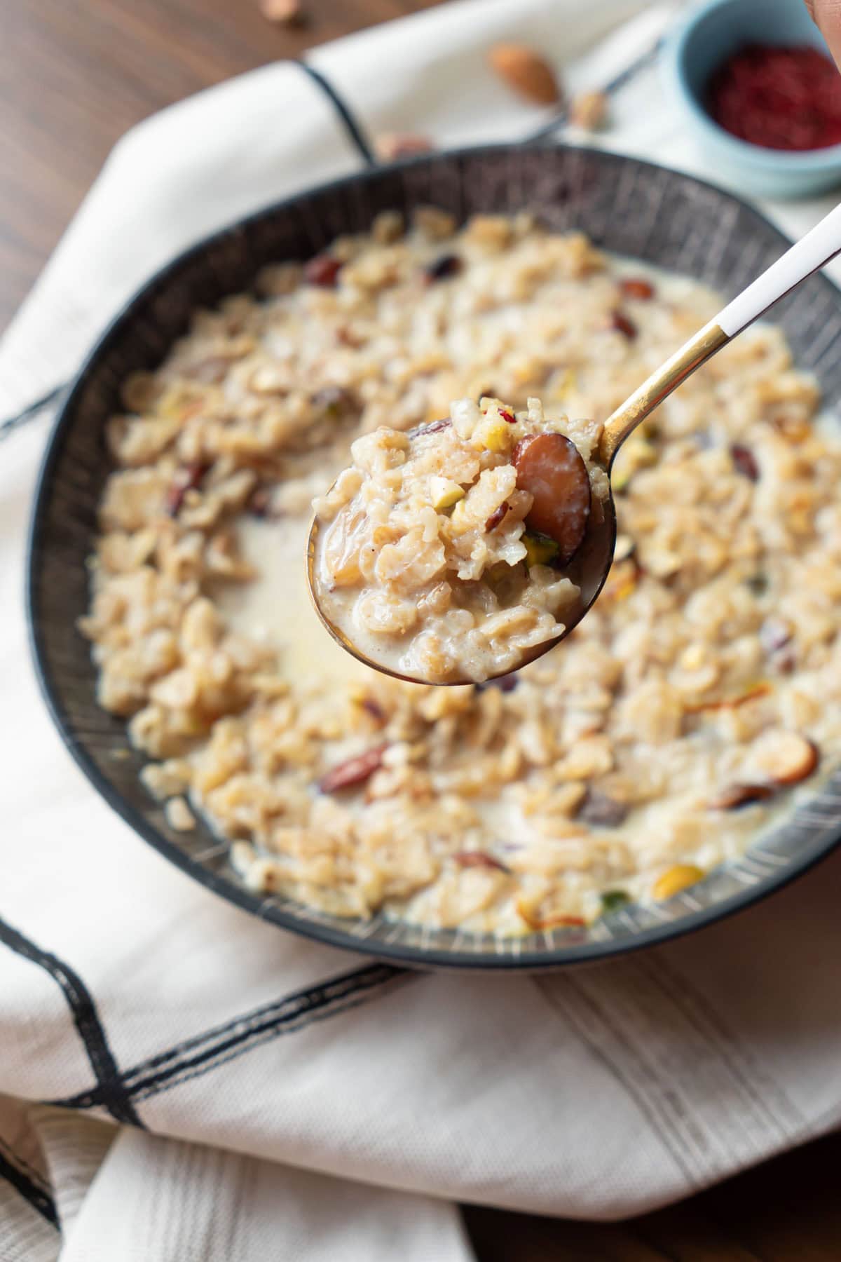 rolled oats kheer in a spoon over a bowl