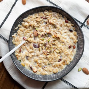 oats kheer served in a bowl topped with nuts and saffron