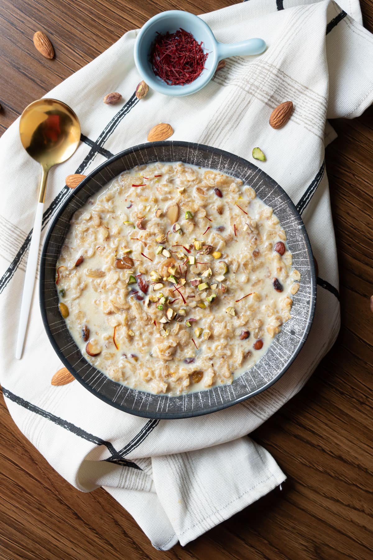 rolled oats kheer in a bowl with pistachios and saffron on top