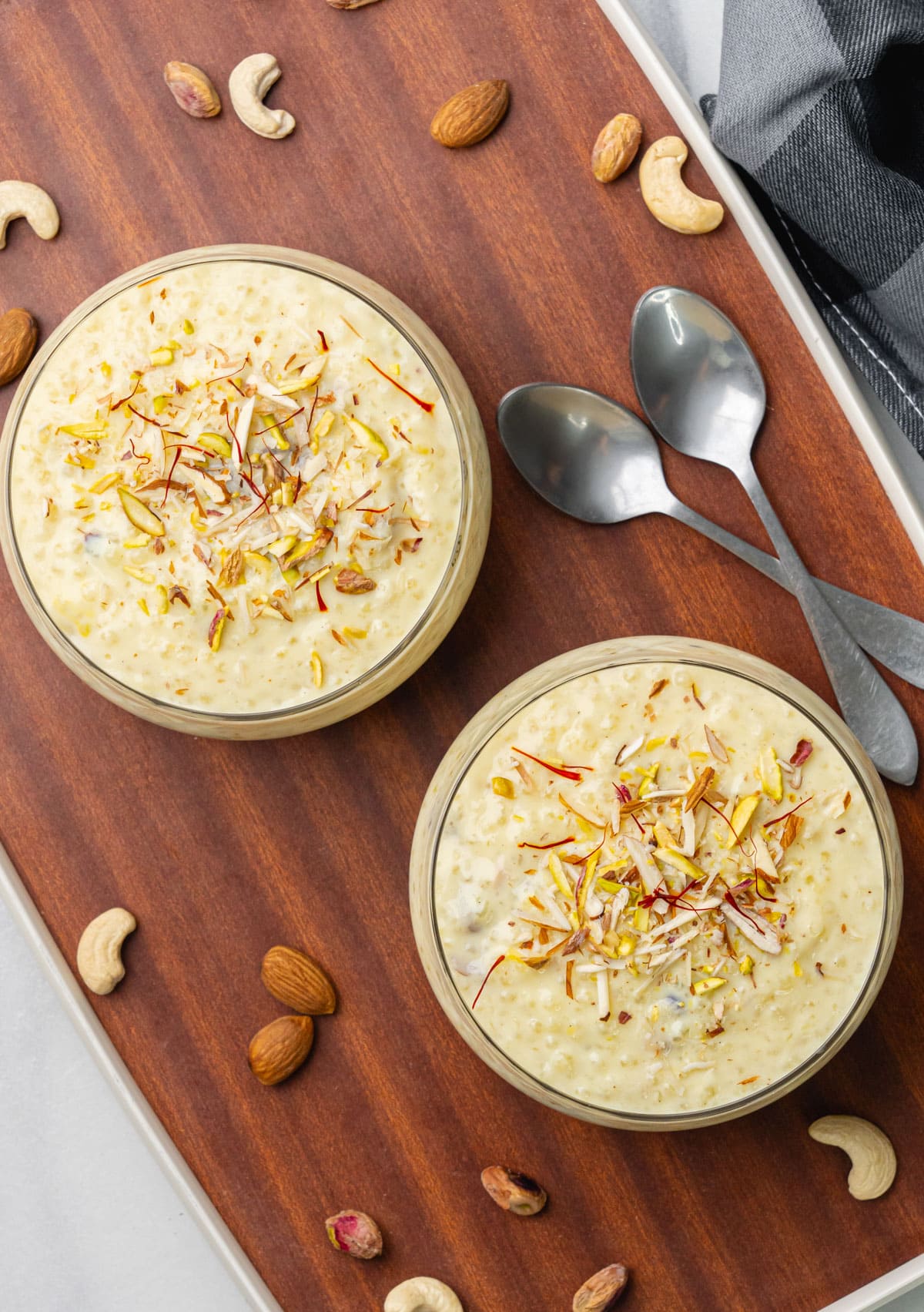 Sabudana kheer in two bowls garnished with nuts and saffron on a tray.