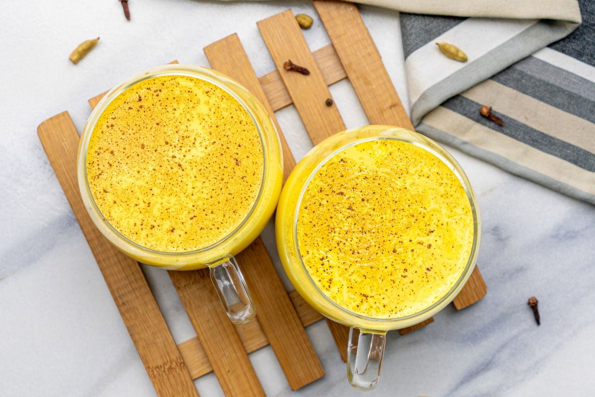Turmeric milk (Haldi doodh) in two cups with sprinkled cinnamon powder