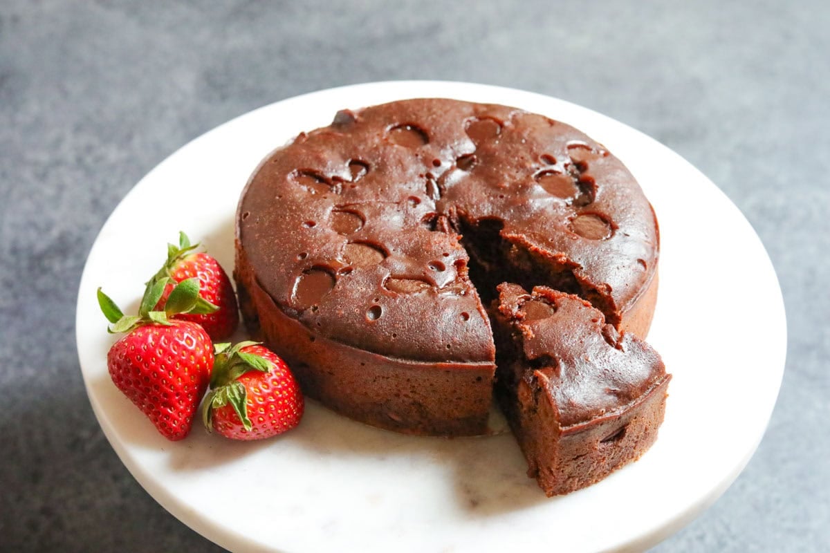 Instant pot brownies on a white plate, with a slice and fresh strawberries