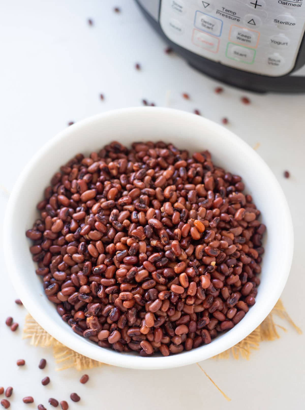 Close-up shot of adzuki beans in a white bowl, with an Instant Pot in the background.