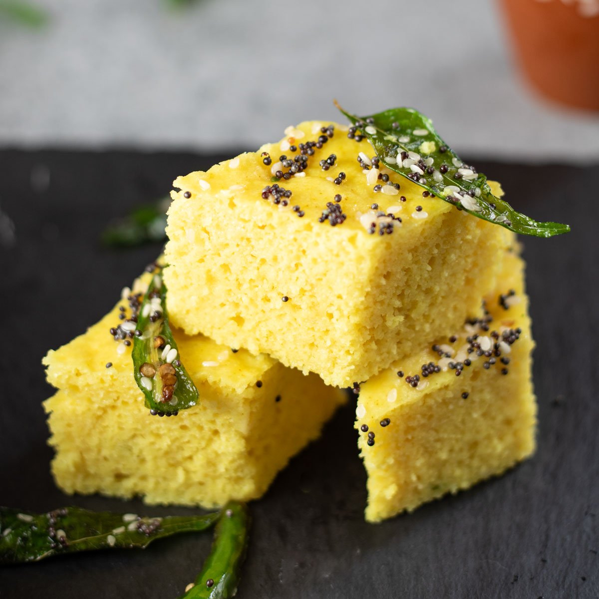 Khaman Dhokla with tempered with green chili and curry leaves stacked.