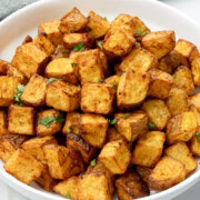 Air fryer diced potato in a white bowl garnished with cilantro