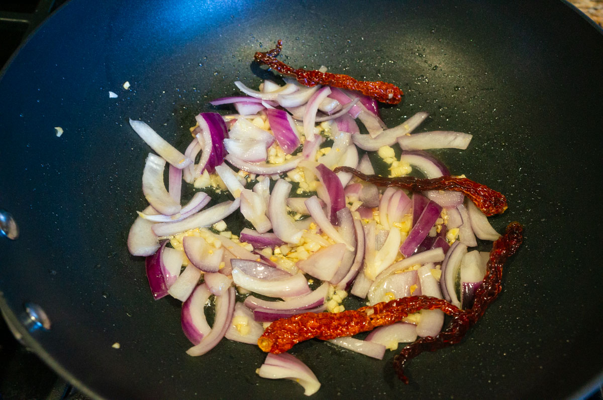 Saute ingredients in a pan to make garlic chili potatoes