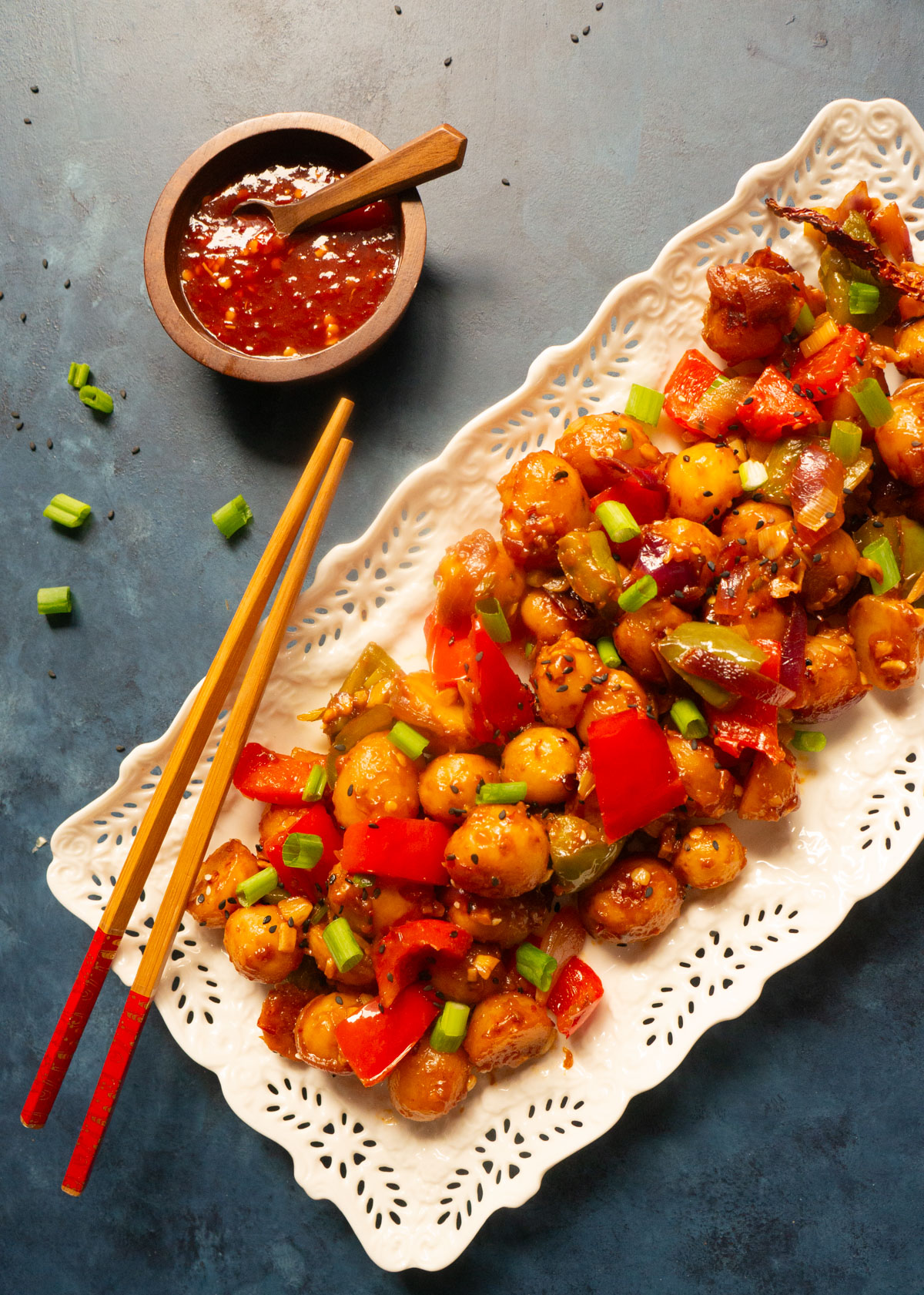 Flavorful and easy Garlic Chili Potatoes, made with steamed potatoes, garlic, chili sauce and honey, sprinkled with green onions and sesame seeds. Enjoy them as an appetizer or side! Chili garlic potatoes on a serving plate with chopsticks