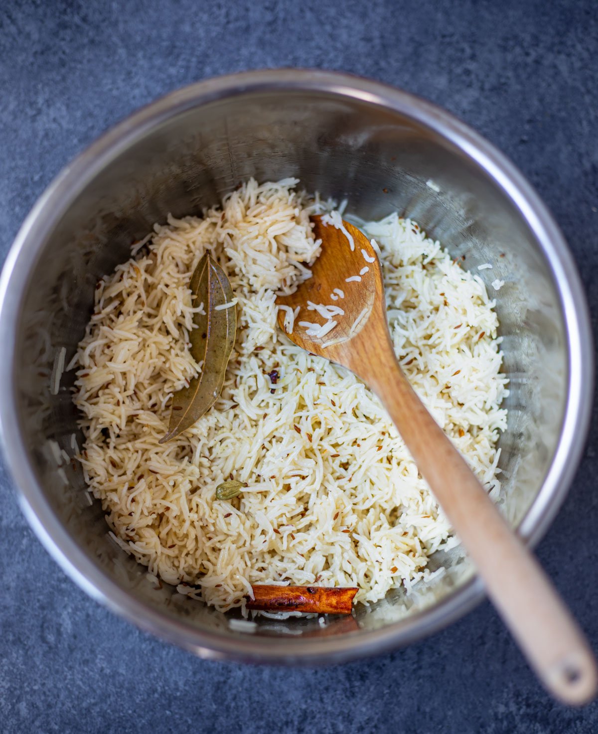 Perfectly cooked jeera rice in a bowl with a wooden ladle