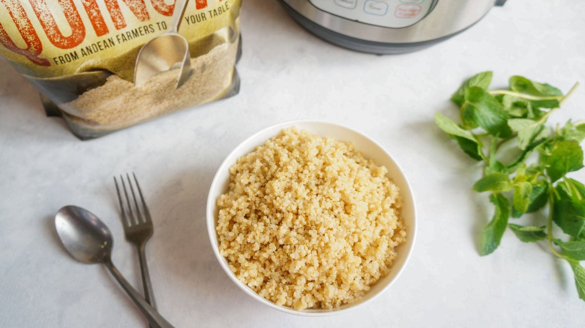 Quinoa in a white bowl with instant pot as a background