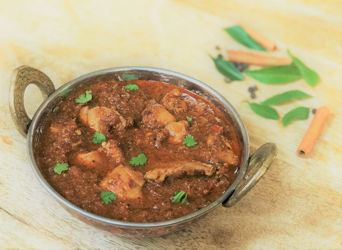 Chicken chettinad in a kadai, garnished with cilantro