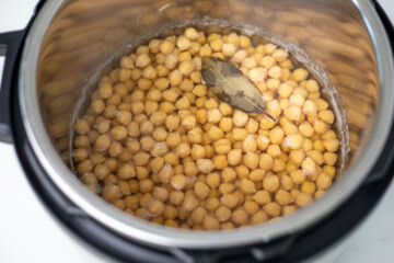 Cooked chickpeas in the instant pot with a bay leaf.