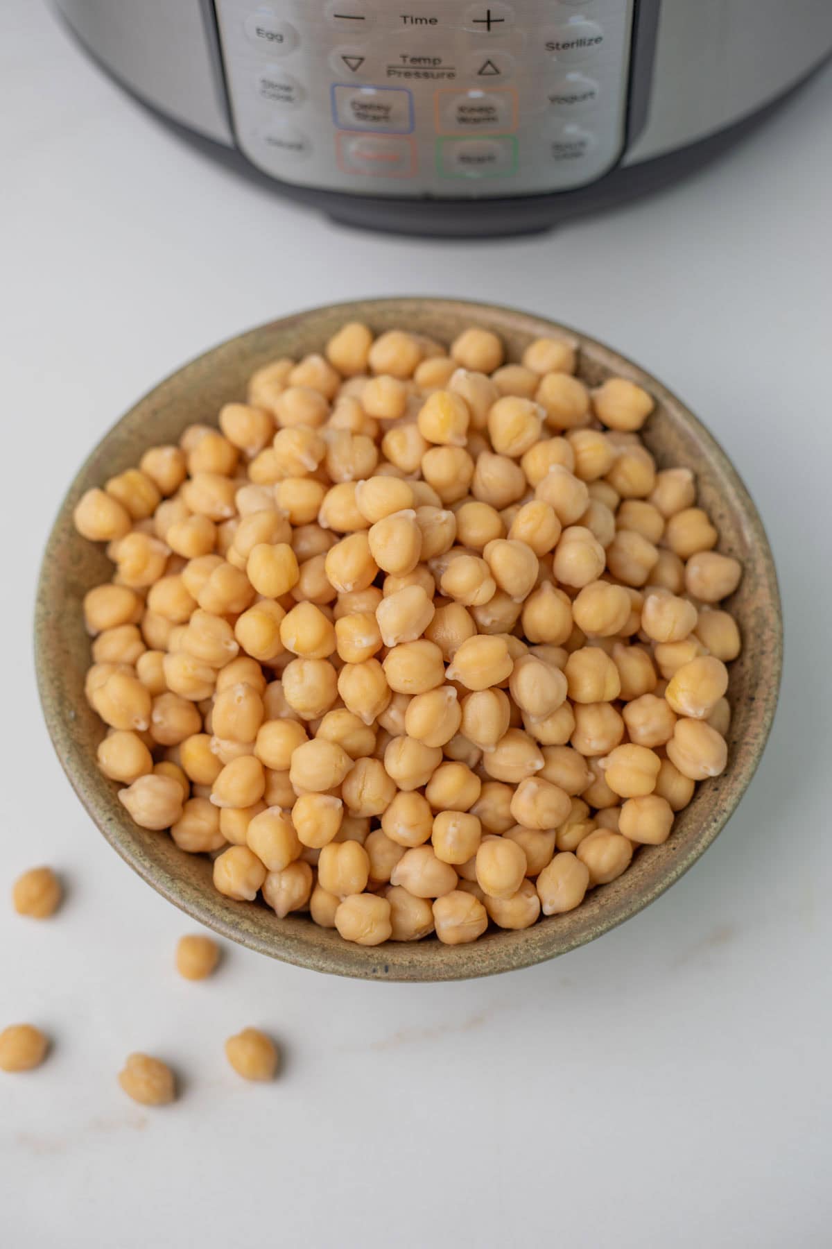 A bowl of cooked chickpeas placed in front of the instant pot.