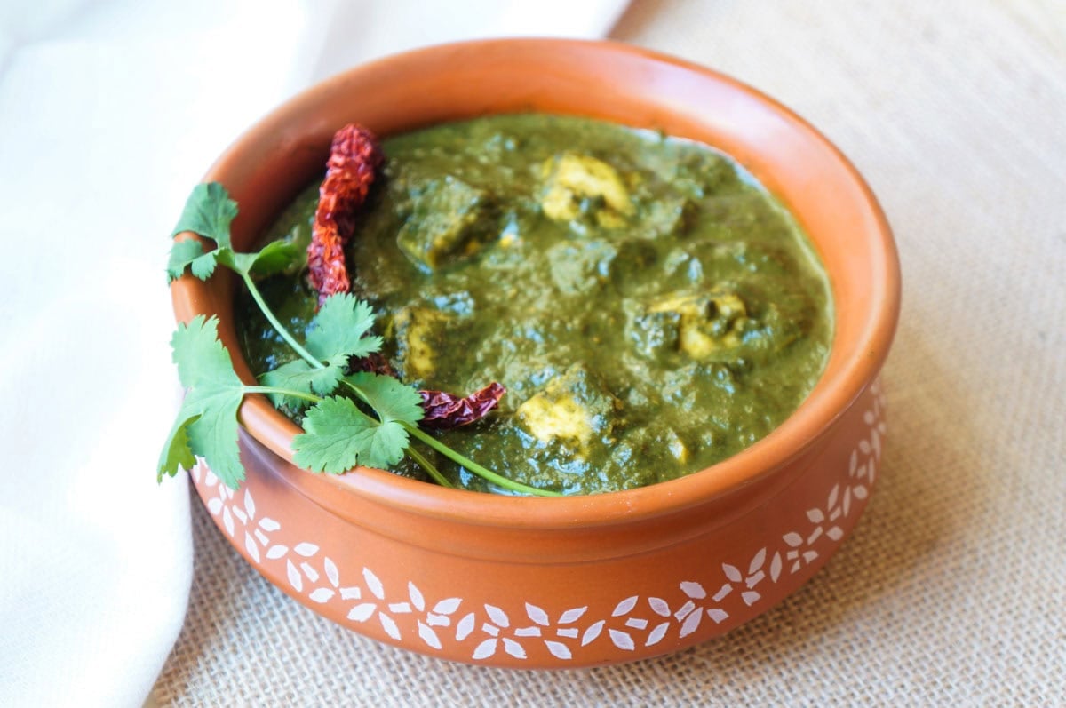Palak paneer in a bowl garnished with fried chili and cilantro
