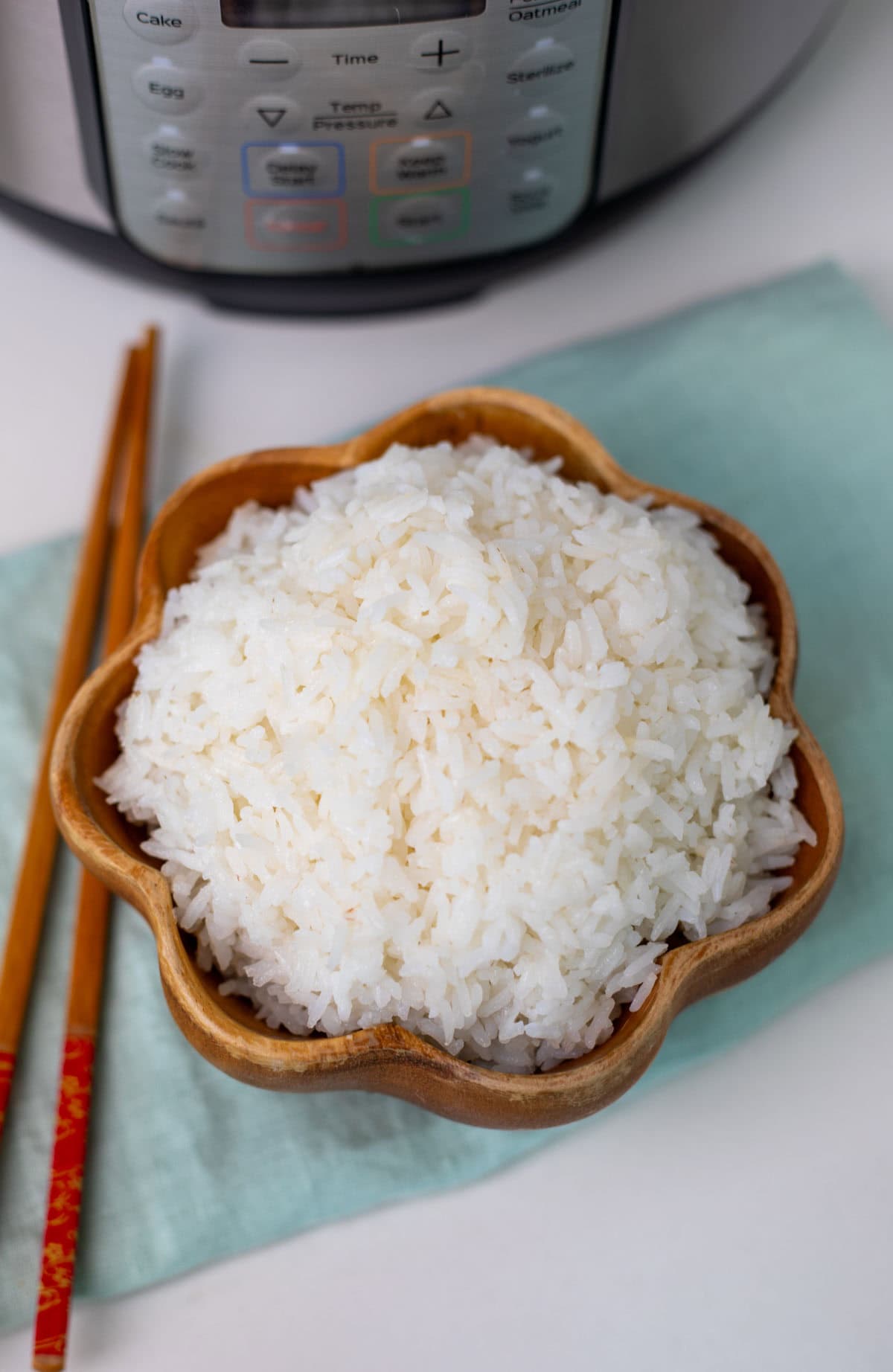 top view of cooked jasmine rice in a wooden bowl with chopsticks on side