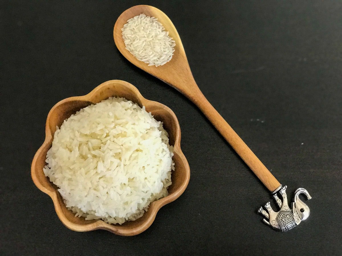 Cooked jasmine rice in a bowl and uncooked rice in a laddle