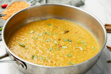 Cooked masoor dal garnished with cilantro in a stainless pan
