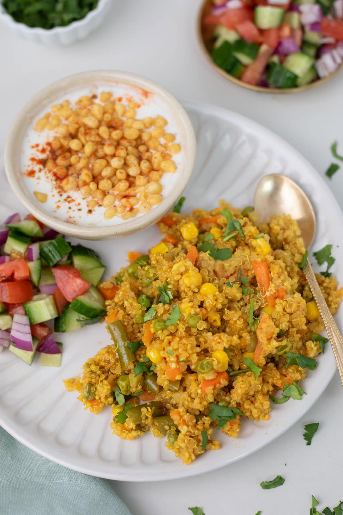 Ready to serve quinoa pulao on a white plate with raita