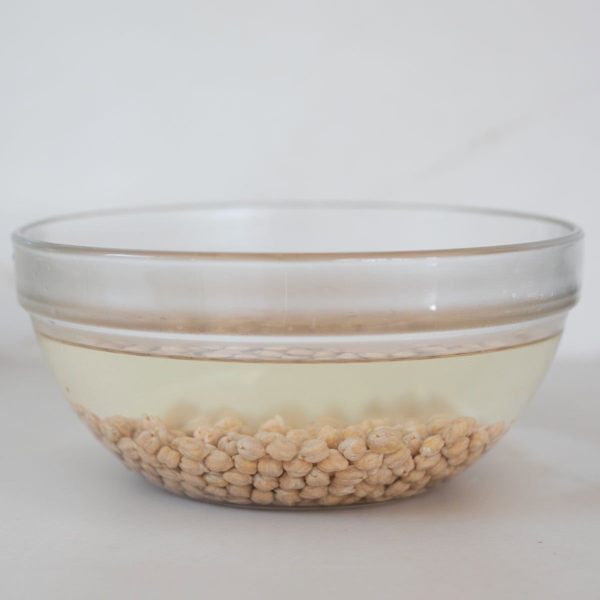 Chickpeas soaked in water in a glass bowl.
