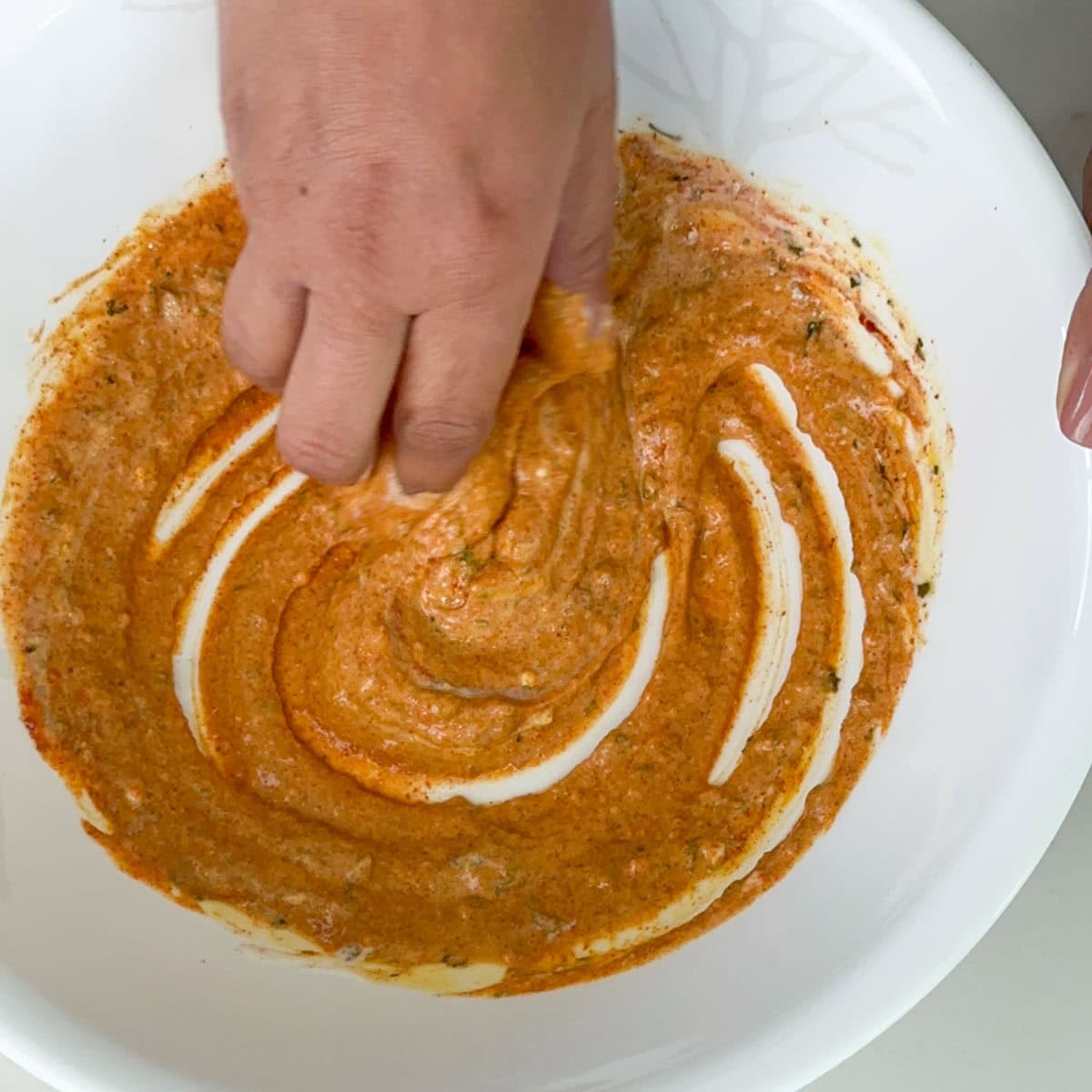 mixing tandoori chicken marinade in a white bowl