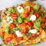 air fryer nachos on a parchment paper garnished with cilantro