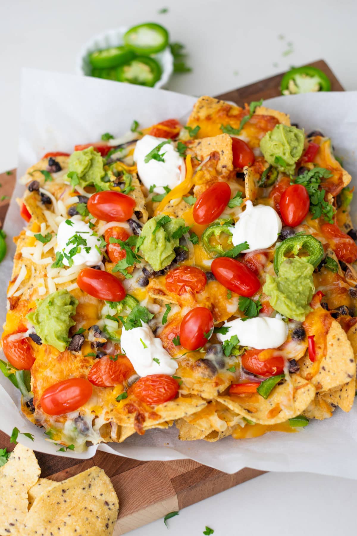 air fryer nachos on a parchment paper garnished with cilantro