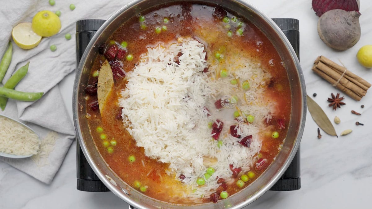 add rice and water into the pan to cook beetroot rice