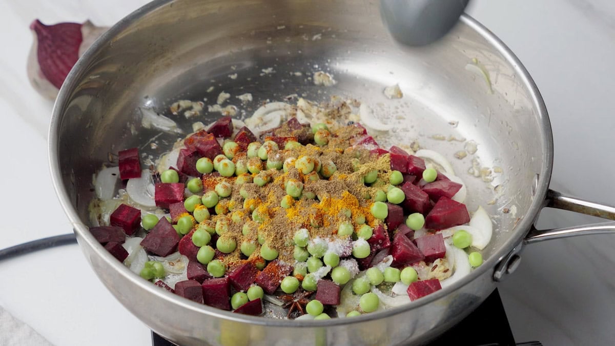 add green peas and spices into the pan to cook beetroot rice