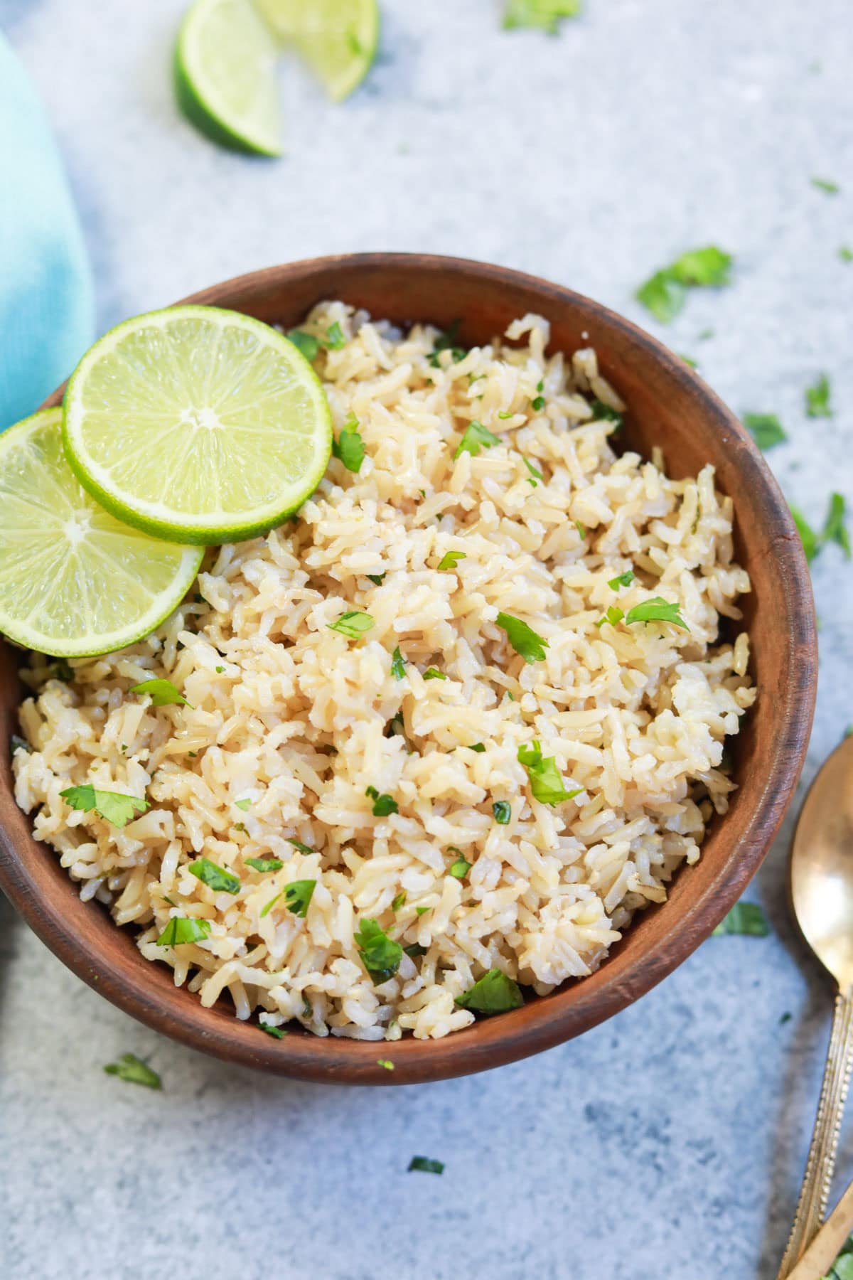 Instant Pot Cilantro Lime Brown Rice served in a brown bowl with lime slices and a spoon