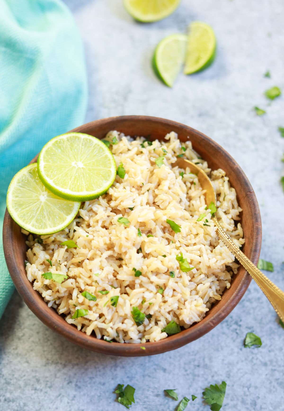 Instant Pot Cilantro Lime Brown Rice served in a brown bowl with lime slices and a spoon