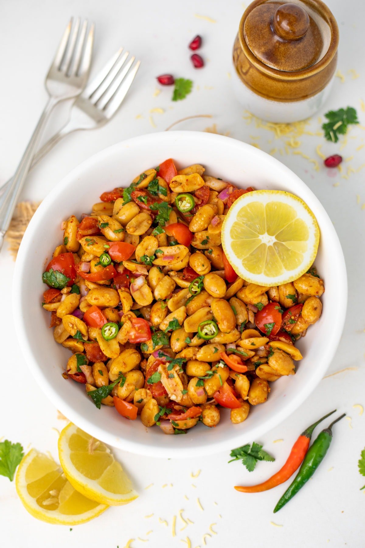 A bowl of peanut chaat with a lemon wedge and a fork