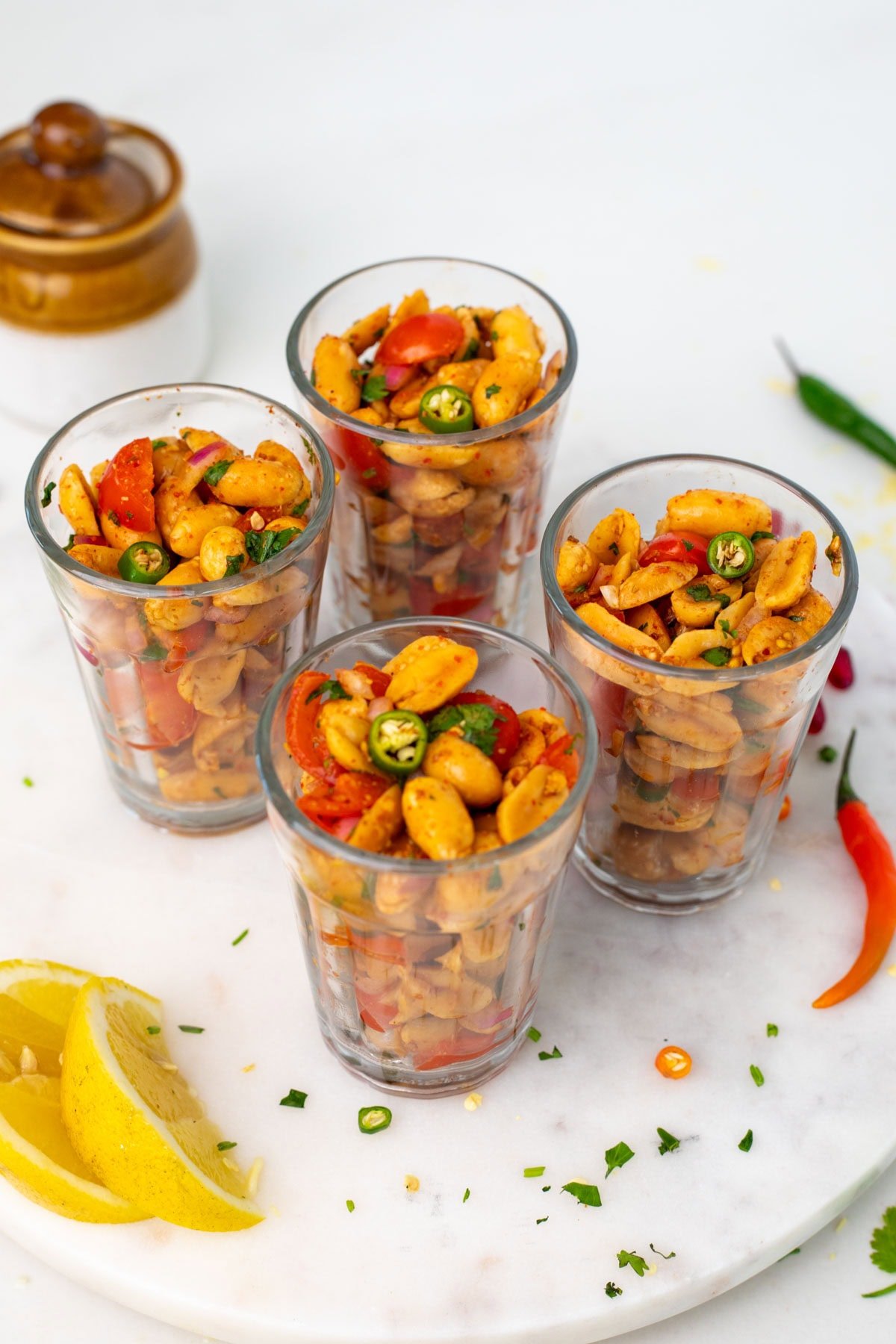 Four cups with peanut chaat on a white plate