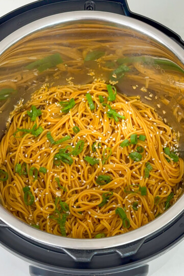Garlic noodles in instant pot garnished with sesame seeds and green onion