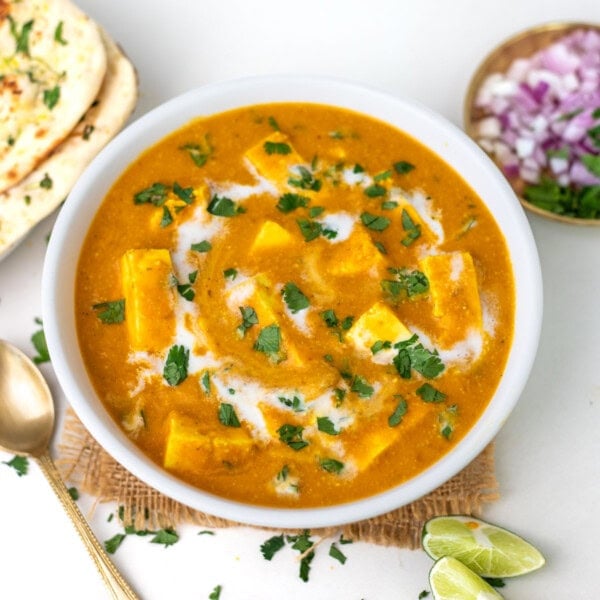 paneer butter masala in a white bowl garnished with cilantro