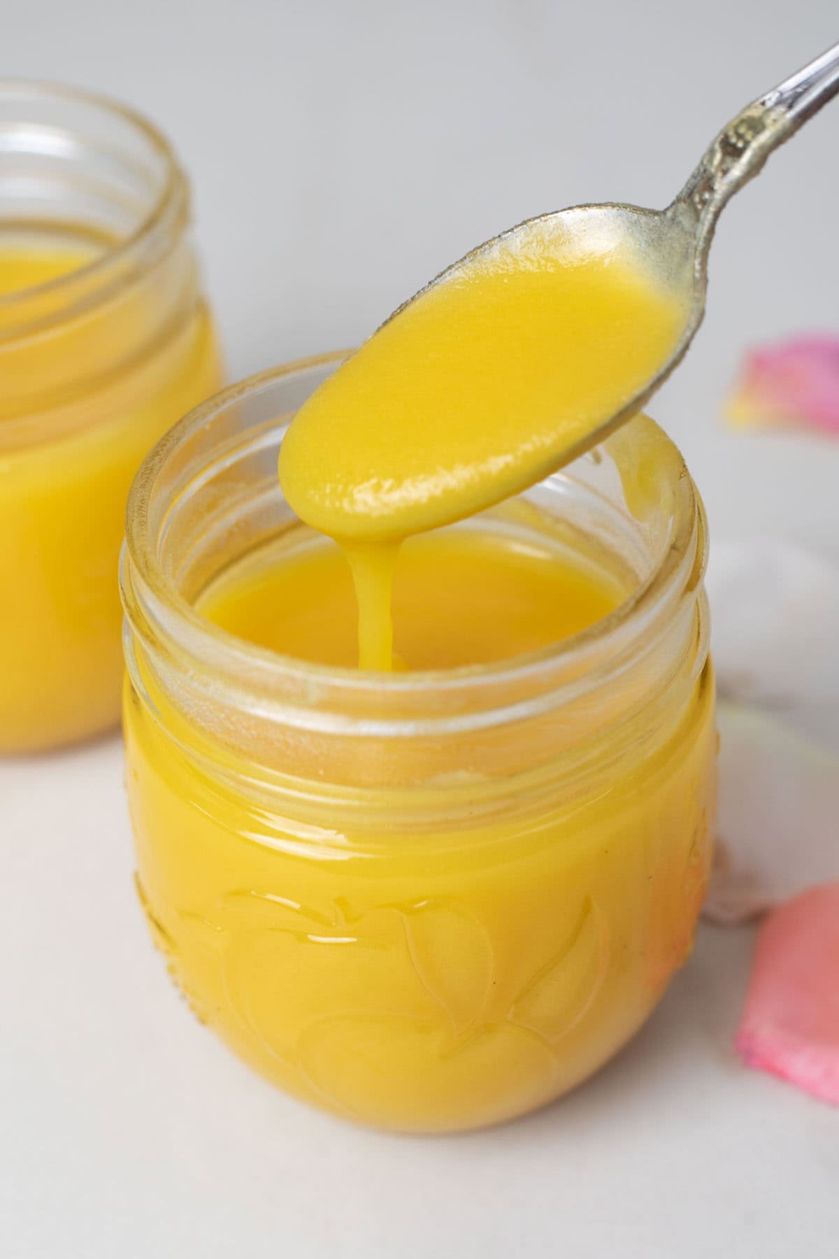 Homemade ghee on a spoon over a jar
