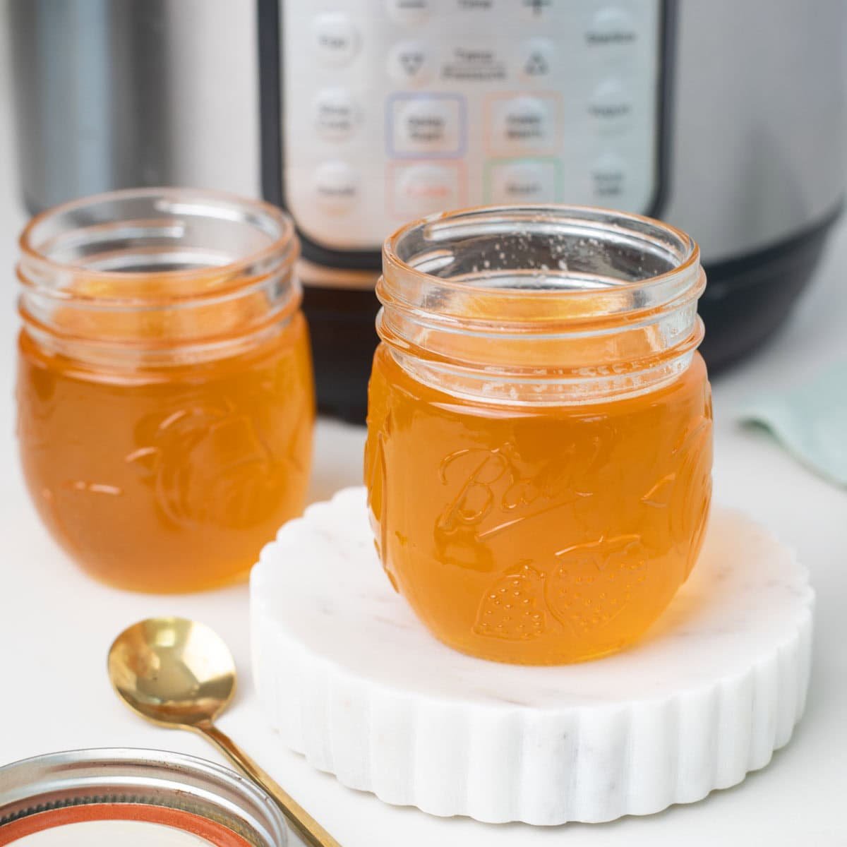 homemade ghee in two glass jar with an instant pot at the background