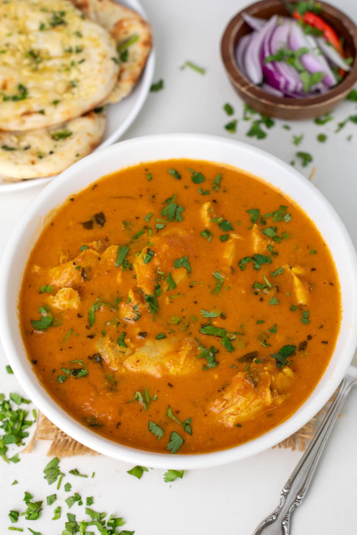 Butter chicken in a white bowl garnished with cilantro