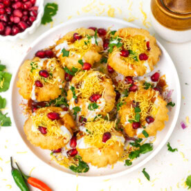 Dahi batata puri on a white plate topped with pomegranate seeds