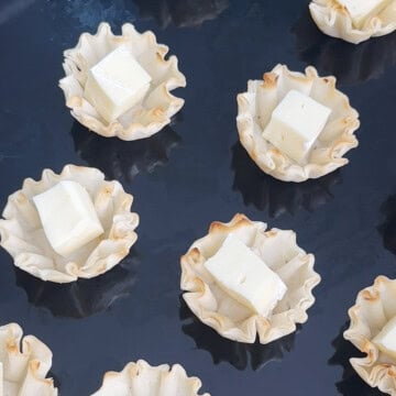 Phyllo Cups topped with brie cubes on a baking tray.