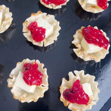 Phyllo Cups topped with brie and cranberry chutney on a baking tray.