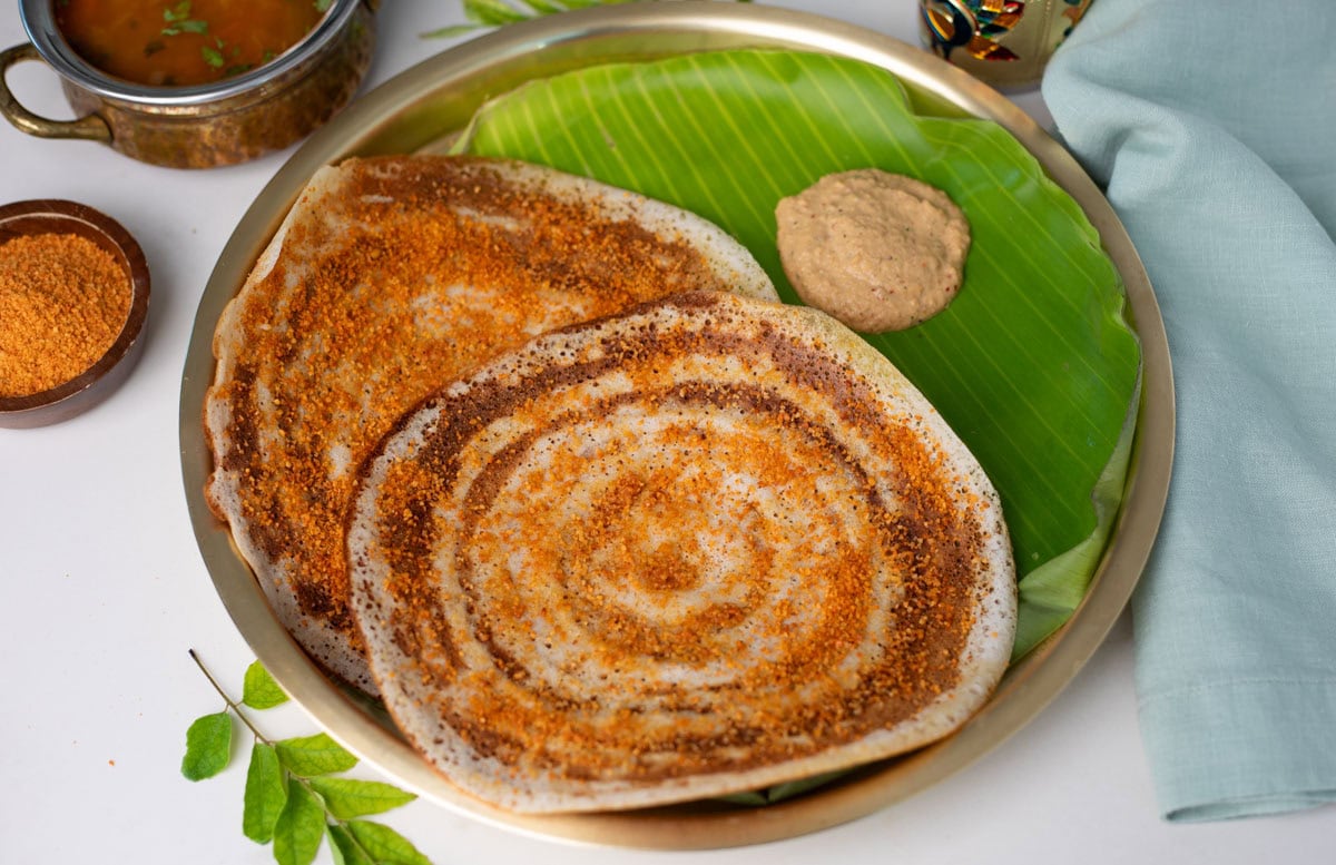 Ready to serve Ghee Podi Dosa on a brass plate wtih chutney on side