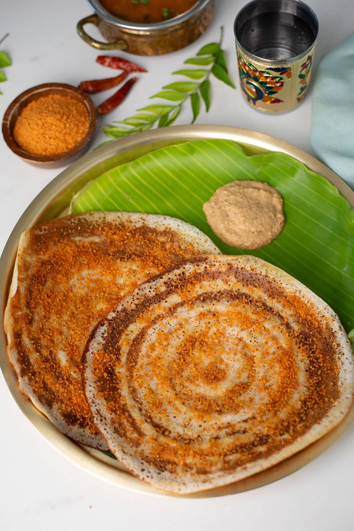 Closeup shot of Ghee Podi Dosa on a brass plate with chutney