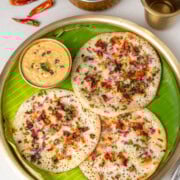 Onion tomato uttapam on a brass plate with chutney and sambar