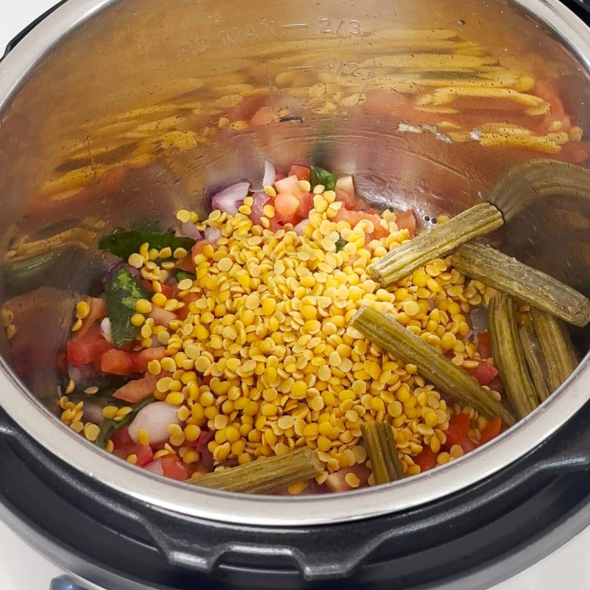 Adding ingredients to make sambar to the instant pot.