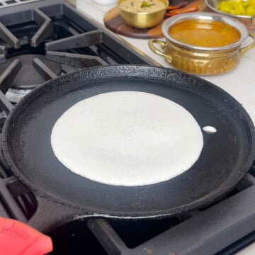Spread uttapam batter on a cast iron pan.