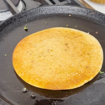 Uttapam cooking on a cast-iron pan