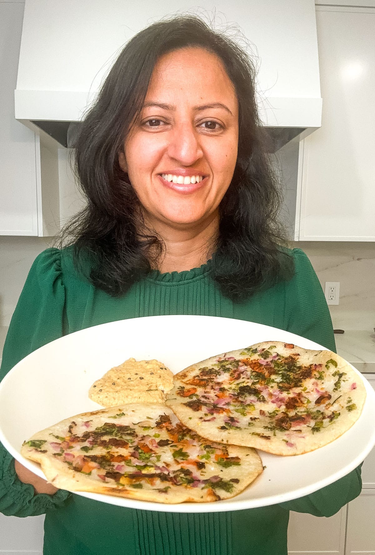 Meeta holding a plate of uttapam with chutney