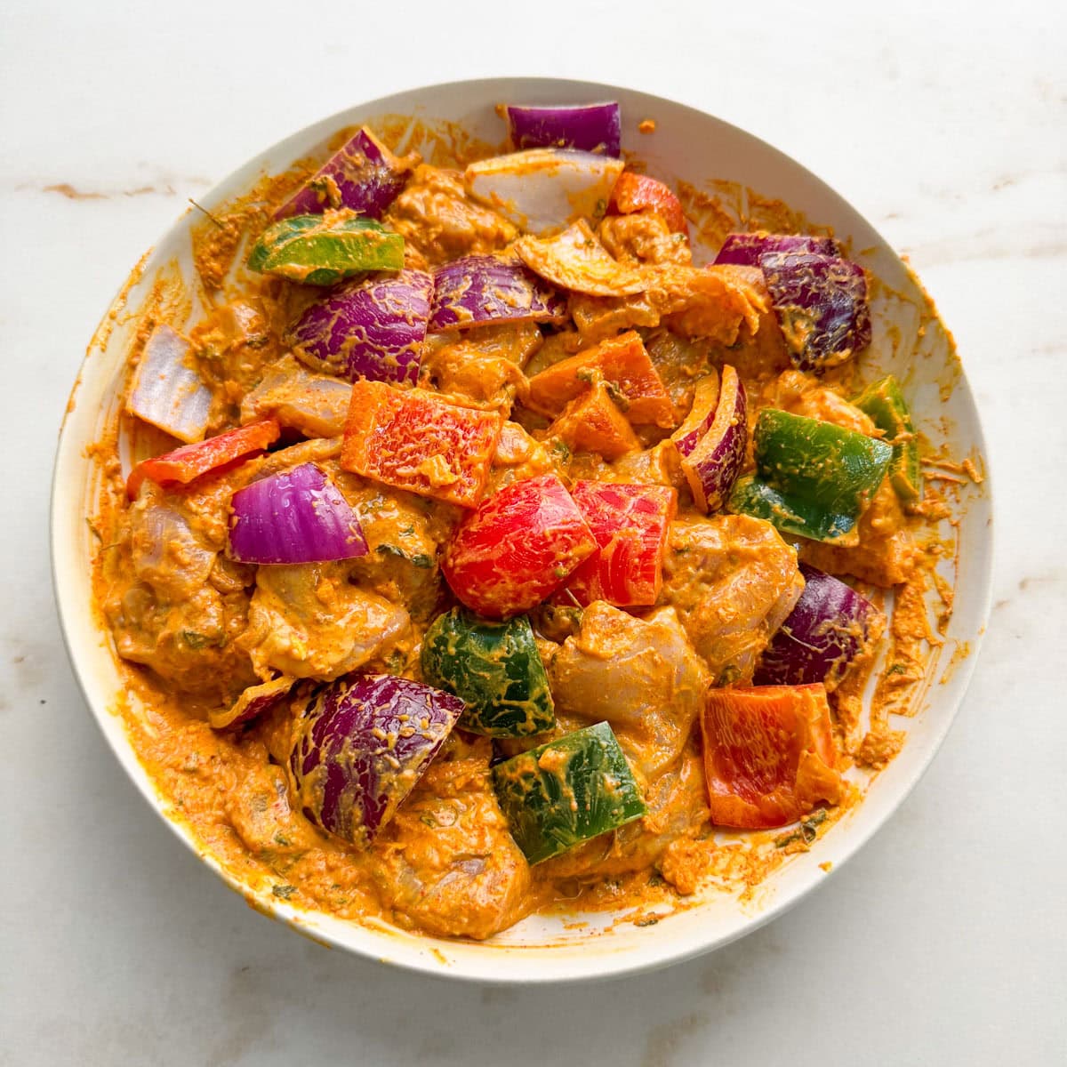 Marinated chicken, red onions and bell peppers for chicken tikka kebabs