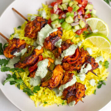 Chicken Tikka Kebab Skewers served over saffron rice with a side of kachumber salad.