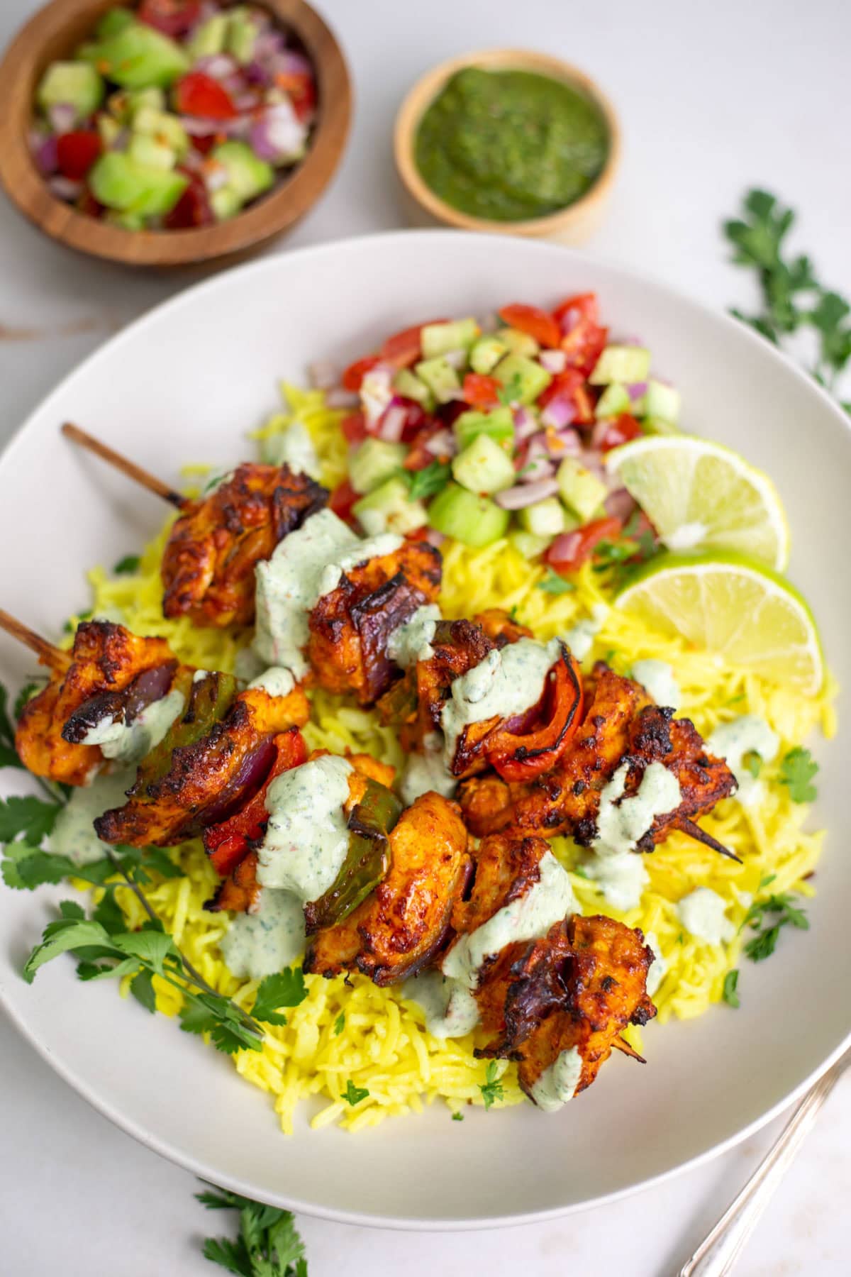 Chicken Tikka Kebab Skewers served over saffron rice with salad and lime on the side.