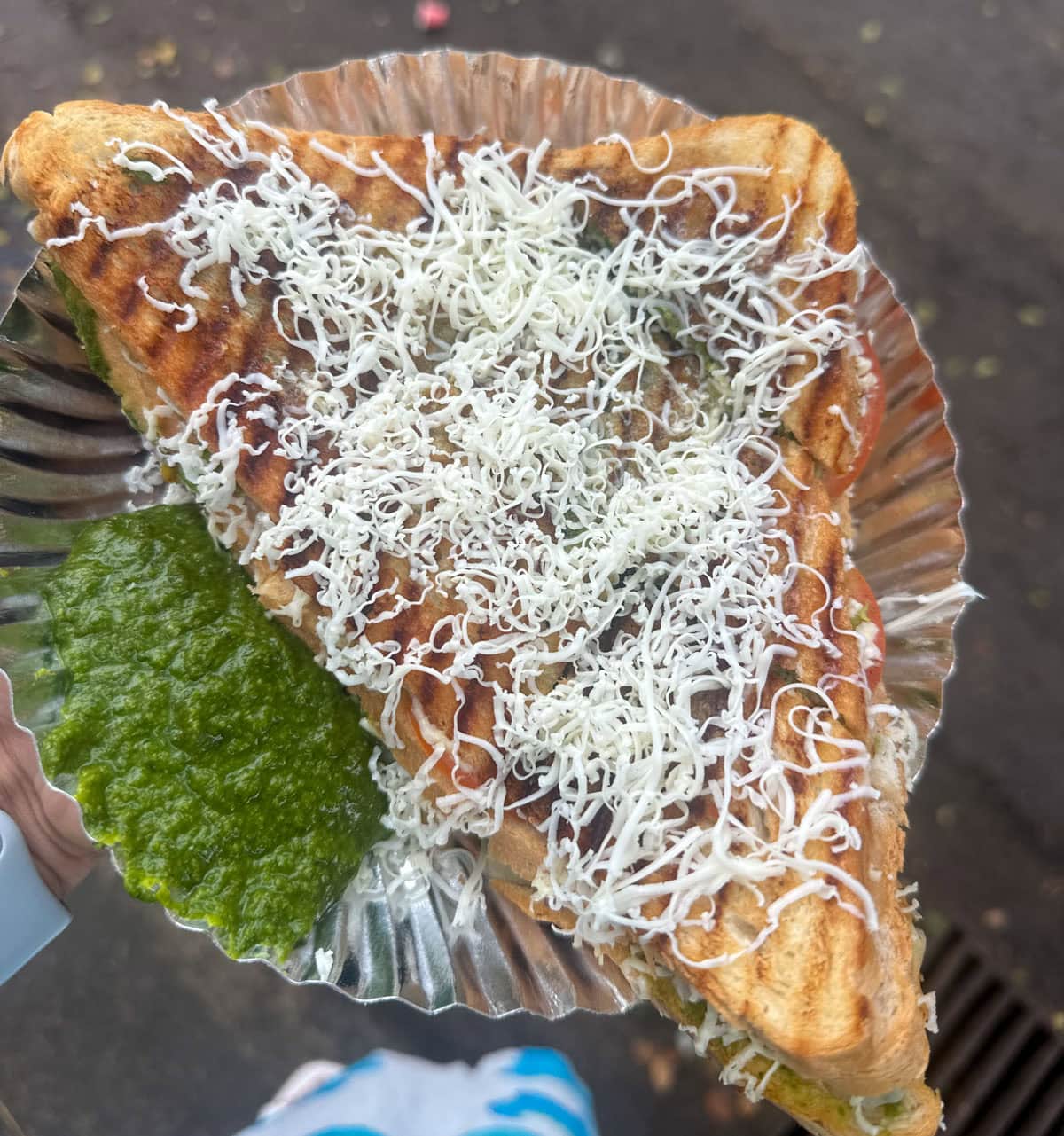 Bombay Sandwich topped with grated cheese and a side of green chutney